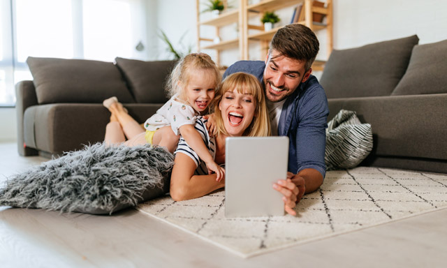 Familie liegt auf Fußboden mit Tablet in der Hand